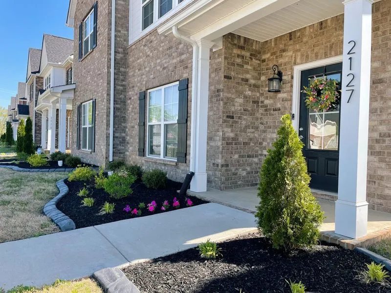 Brick home with fresh mulch beds, flowering plants, and stone-edged walkway